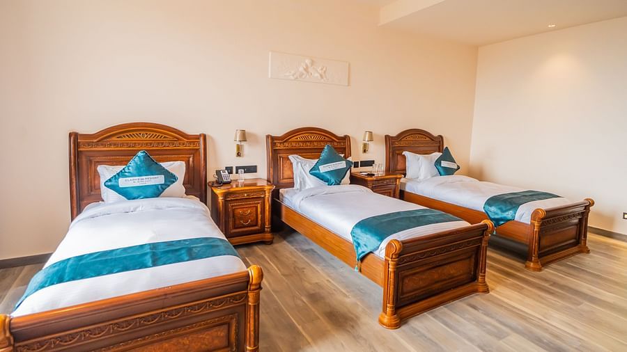 an image of a bedroom with three beds and wooden finished flooring.